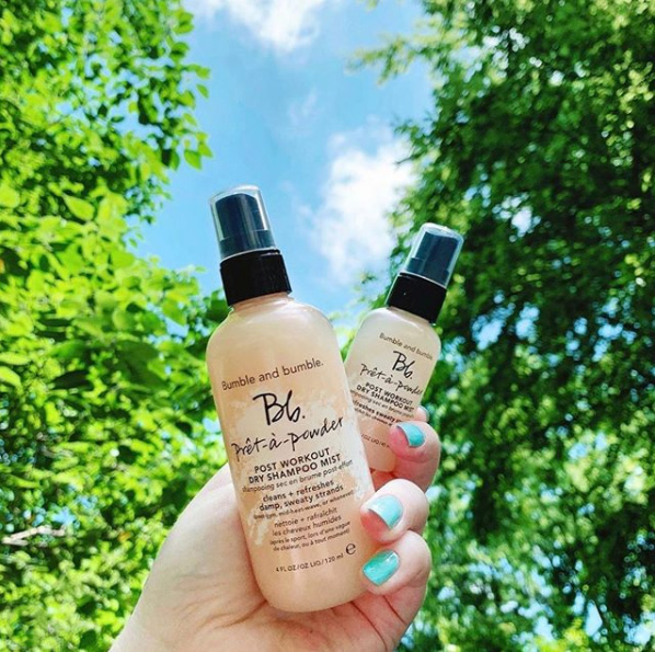 Hand holding two Bb products; trees and sky in background